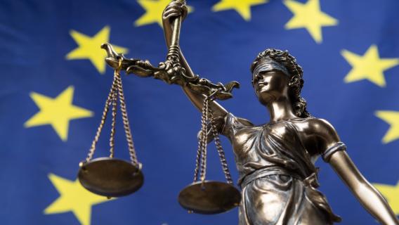 Statue de justice sur fond de drapeau européen