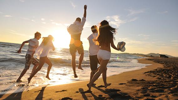 Un groupe de jeunes gens, heureux, sur une plage de sable dans le soleil couchant