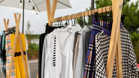 Un portant de boutique est rempli de vêtements en exposition.