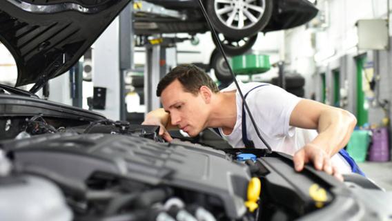 Un garagiste examine le moteur sous le capot d'une voiture