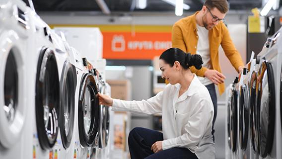Un couple examine des lave-linges dans un rayon de magasin avant de faire son choix