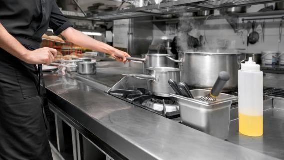 Cuisine de restaurant, un employé manipule des casseroles 
