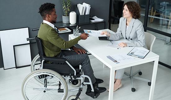 Une personne en fauteuil roulant discute avec un recruteur autour d'un bureau