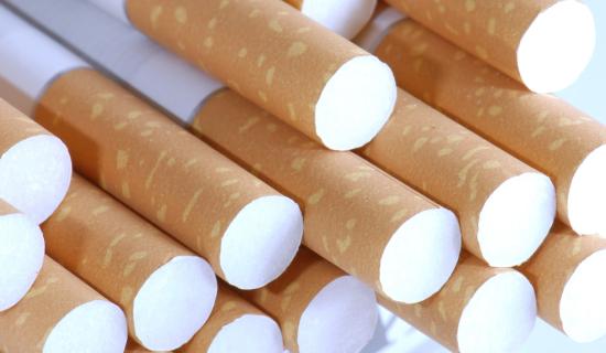  gros plan sur un ensemble de cigarettes neuves, disposées de manière serrée et orientées de façon à ce que l’on voie l’extrémité avec le filtre blanc et le papier brun clair tacheté caractéristique.