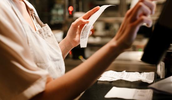 Hôtesse de caisse saisissant des factures sur son ordinateur